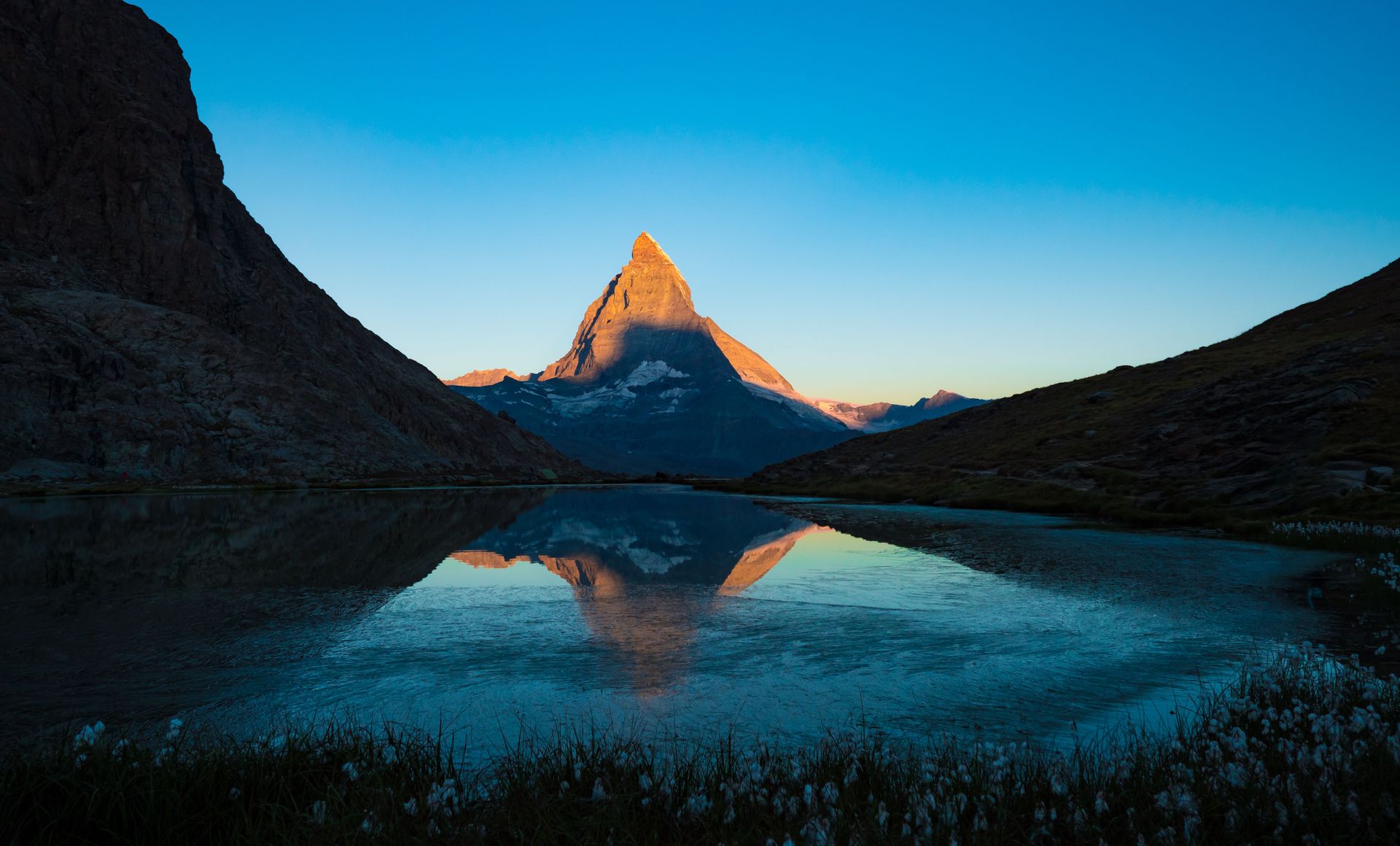 Sunlit mountain peak reflected in an alpine lake